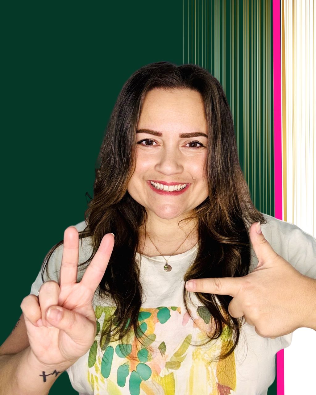 Frau mit langen dunklen Haaren lächelt in die Kamera und zeigt mit den Händen das Peace-Zeichen und ein geformtes "L" vor einem Hintergrund mit dunkelgrünen und goldenen vertikalen Streifen.